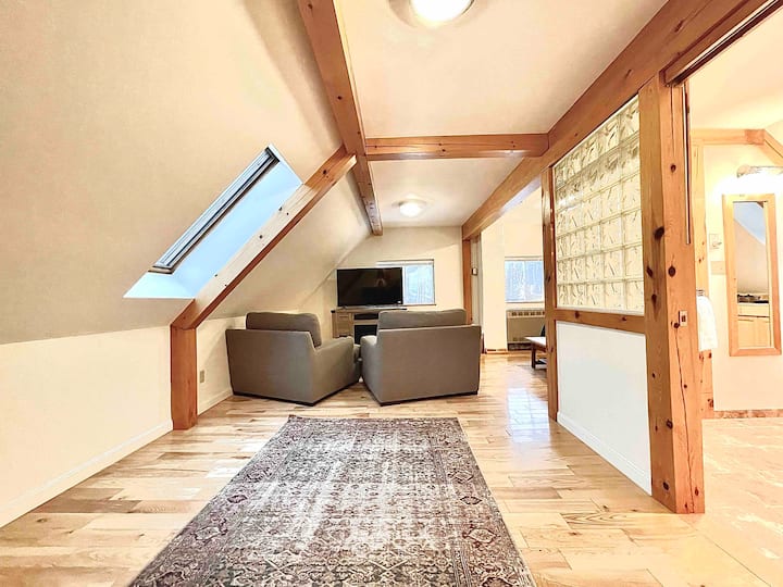 Главна спална соба со брачен кревет, простор за седење, електричен камин и 55-инчен Roku телевизор. 