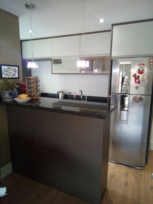 Vista da sala para a cozinha: bancada multiuso e geladeira duplex.