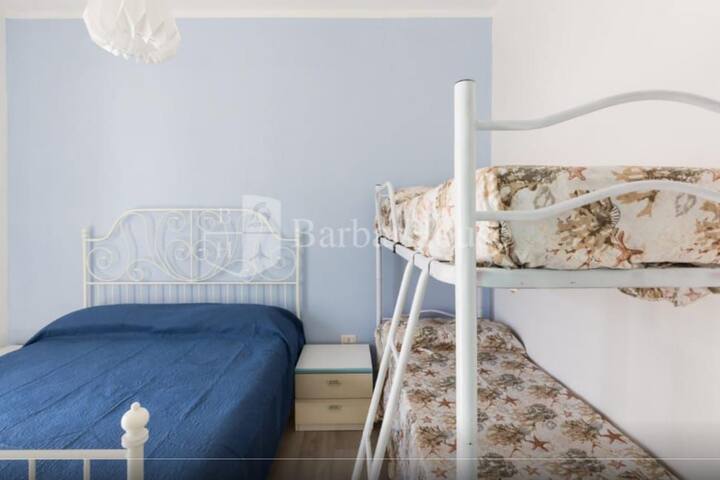 ห้องนอนพร้อมเตียงคู่และเตียงสองชั้นพร้อมตู้ไม้แขวนเสื้อและเครื่องปรับอากาศพร้อมรีโมทคอนโทรล