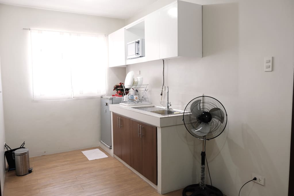 Small kitchen with fridge, microwave, water pot, plates, glasses & utensils you can use
