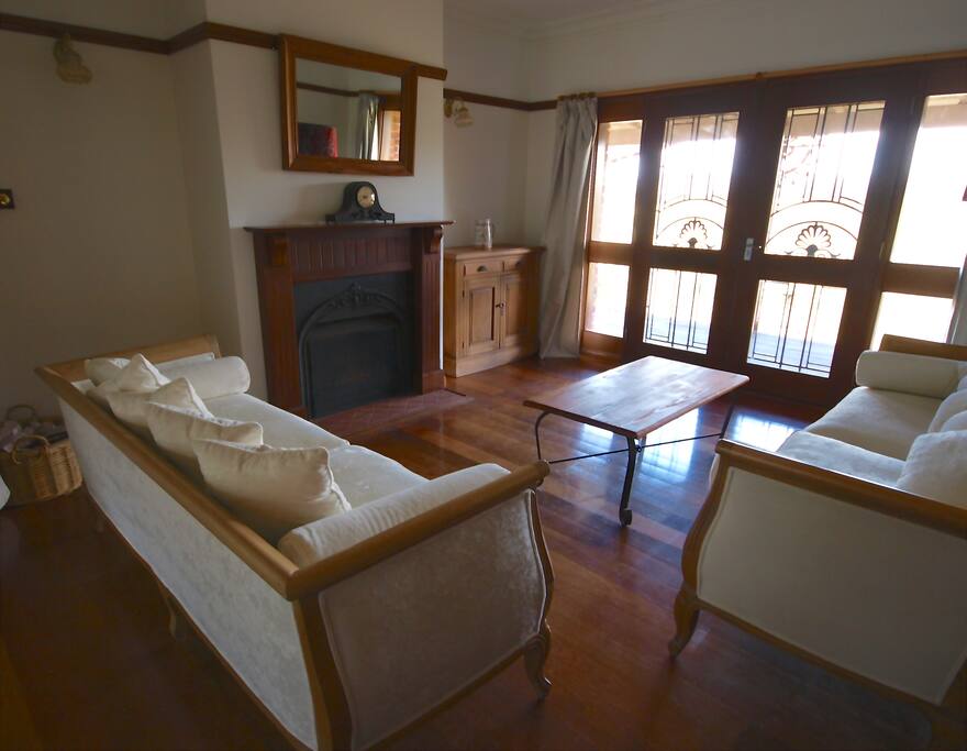 Lounge room with open fireplace opening onto front verandah.