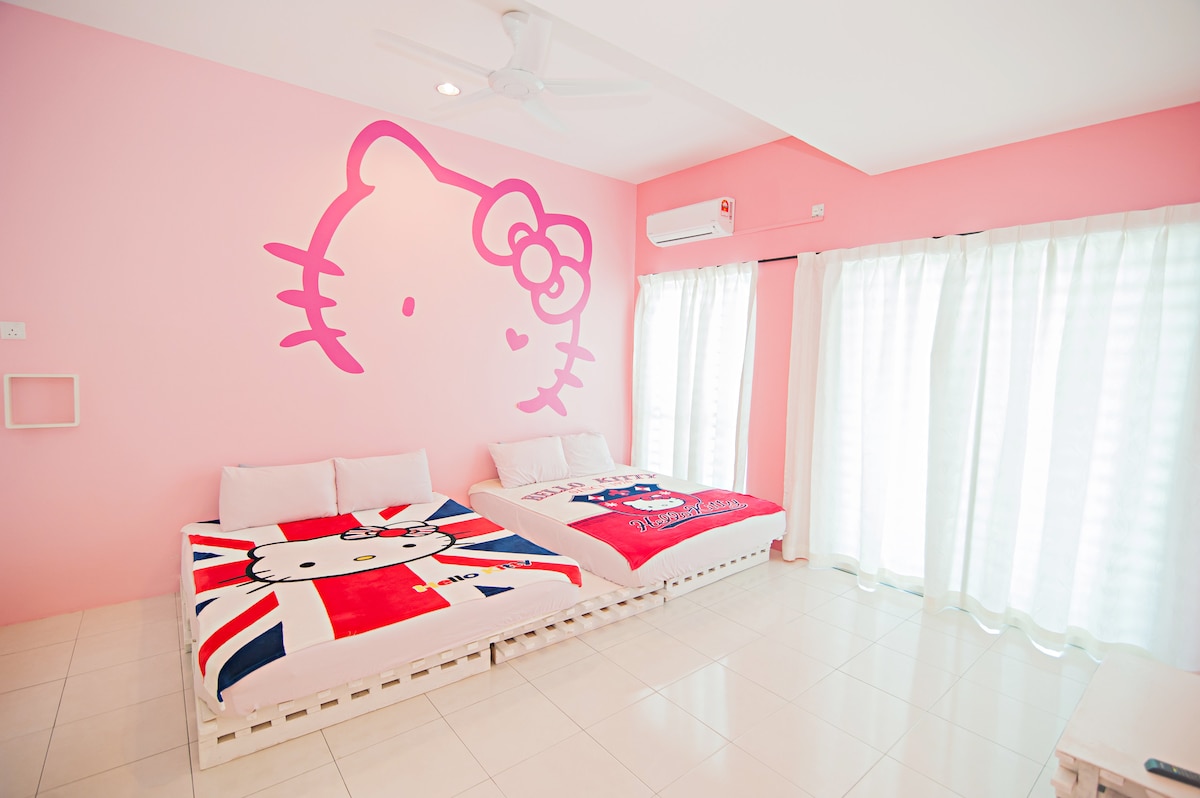 A bright room features twin double beds adorned with colorful bedding, including a Hello Kitty design. Soft, sheer curtains allow natural light to fill the space, while pink walls enhance the cheerful ambiance. A ceiling fan provides air circulation for comfort.