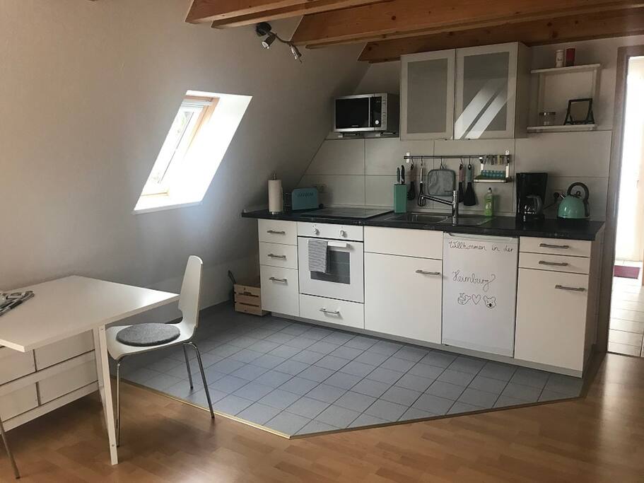 Die Küchenzeile mit Herd, Mikrowelle und Kühlschrank