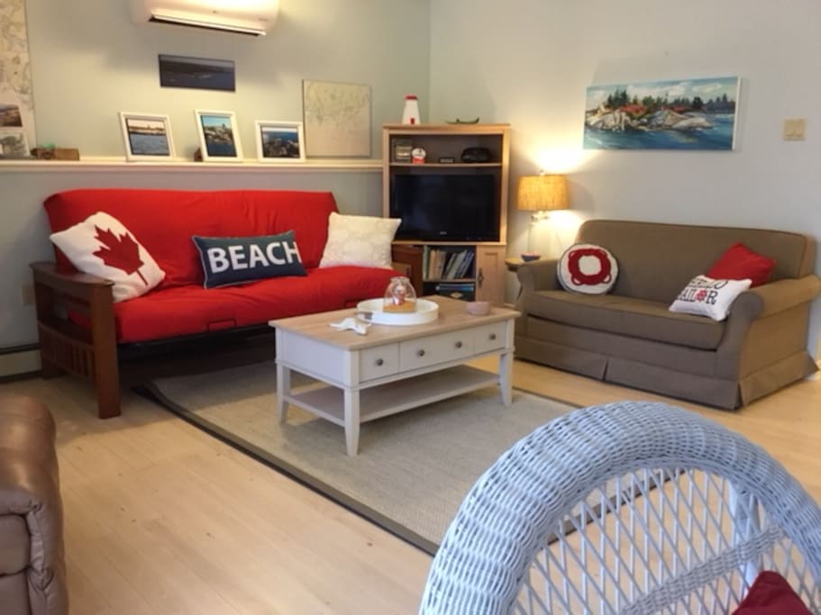 Living area with newly refinished wood floors, new area rug, futon mattress, lamp and coffee table. The unit now has air conditioning. Toasty warm in winter and refreshing in the summer.