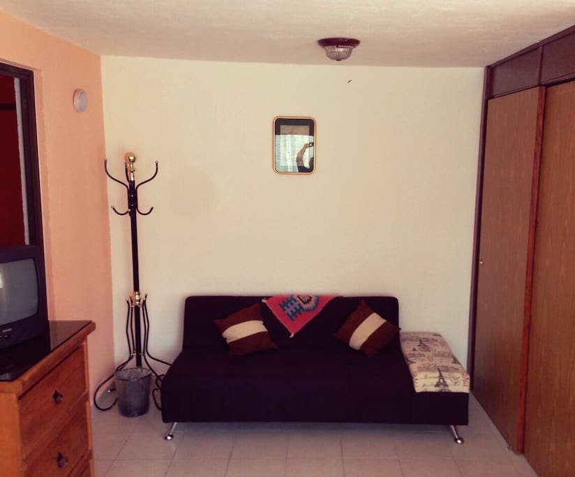 Es una habitación cómoda cuenta con un sofá y un perchero