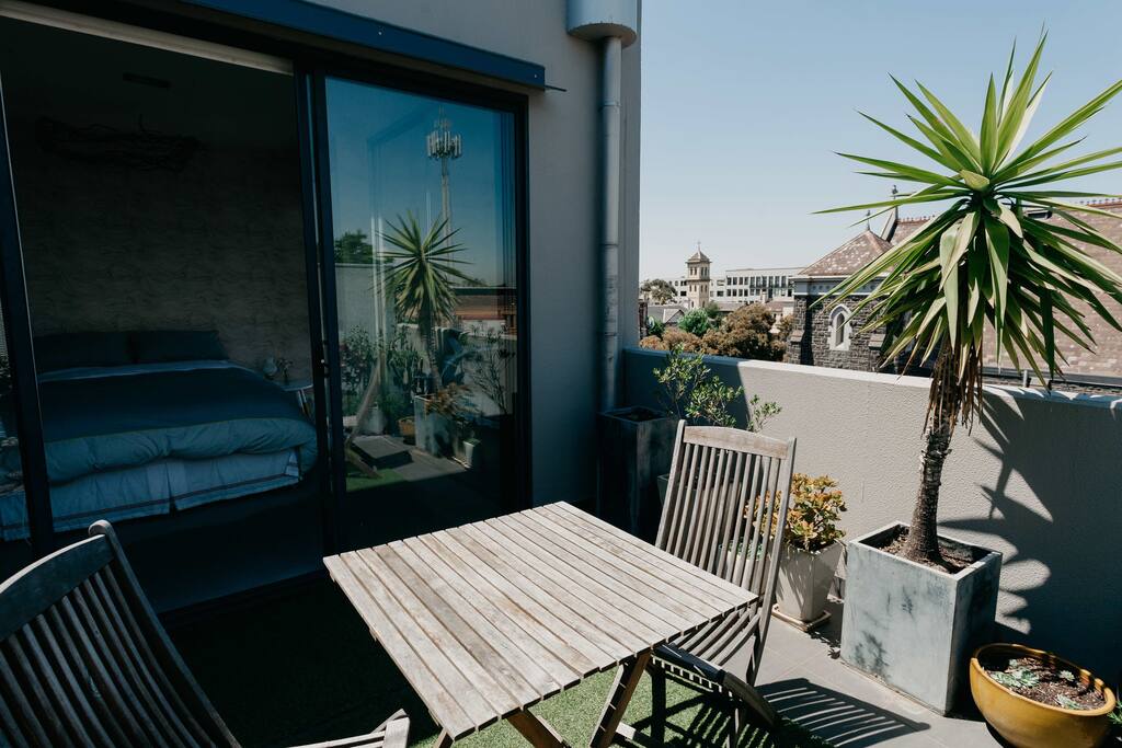 Paradise. The bedroom features floor-to-ceiling windows and a sliding door leading to a beautiful green balcony.