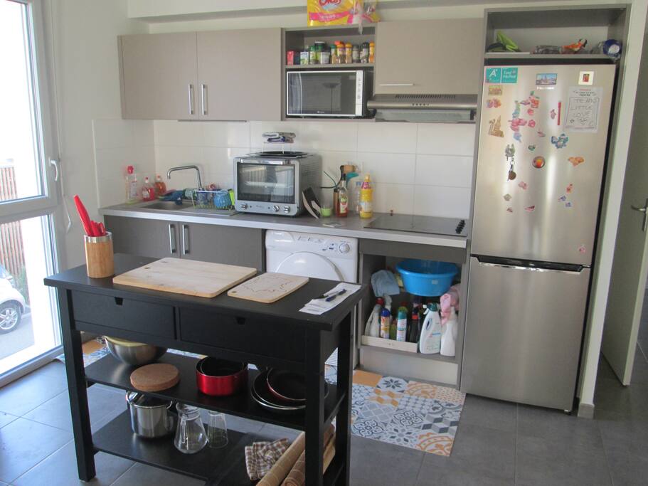 Vu de la cuisine ouverte. Hotte aspirante, grand frigo-congélo, micro-onde, four, table de travail, plaques électrique (4)