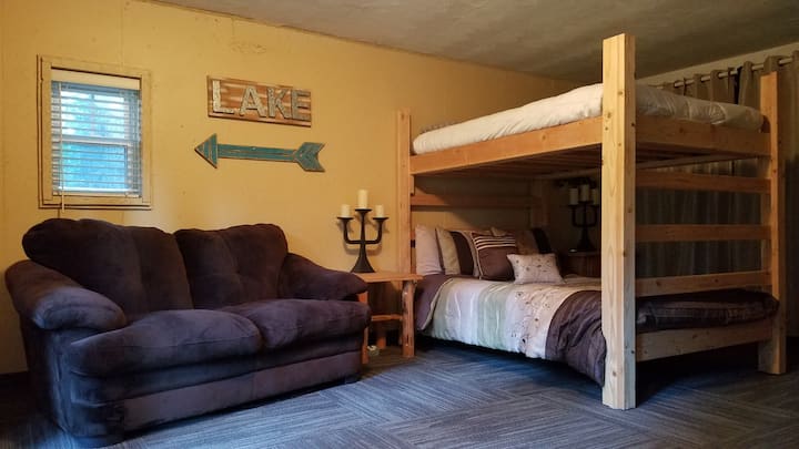 Kelder met ingang via openslaande deuren, met een stapelbed met twee grote bedden en een bank en een liefdeszitje voor comfortabele ontspanningsruimte.