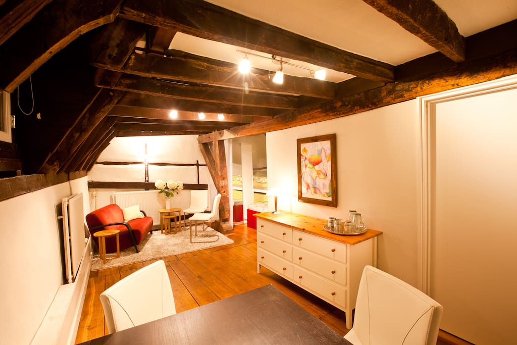 Een ruime kamer met eigen tafel en zitje onder de balken van bijna 700 jaar oud. Rechts achteraan zie je nog een stukje van het bed.