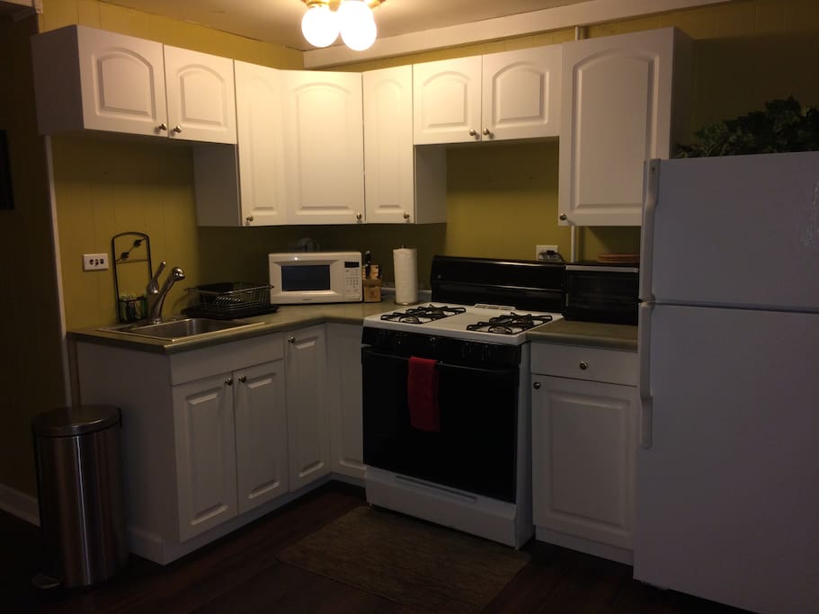 Full kitchen furnished with dinnerware, stovetop, microwave, toaster oven, fridge, and more.