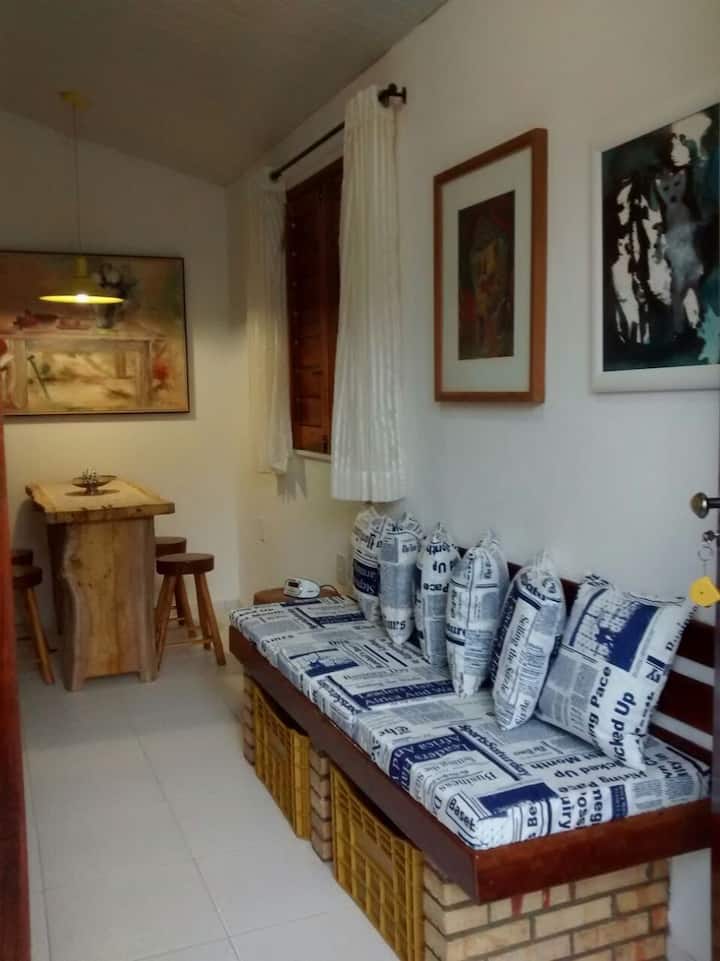 Sofá sala de estar, con espacio inferior para guardar el equipaje. En el fondo, un comedor y estudios.
