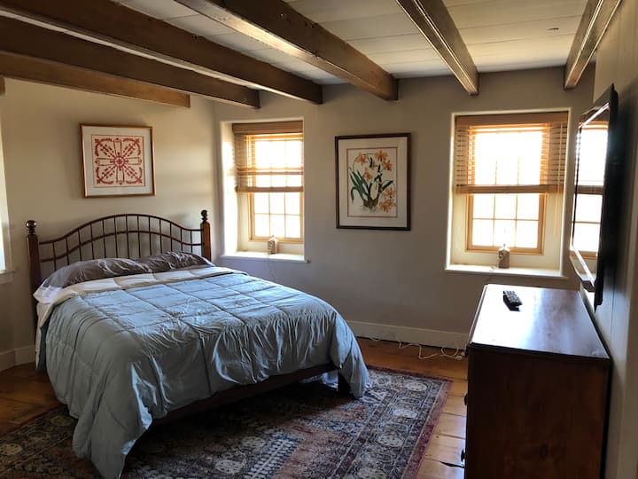 Dormitorio con cama queen size. Sábanas y toallas y batas de toalla que cuelgan en el armario.