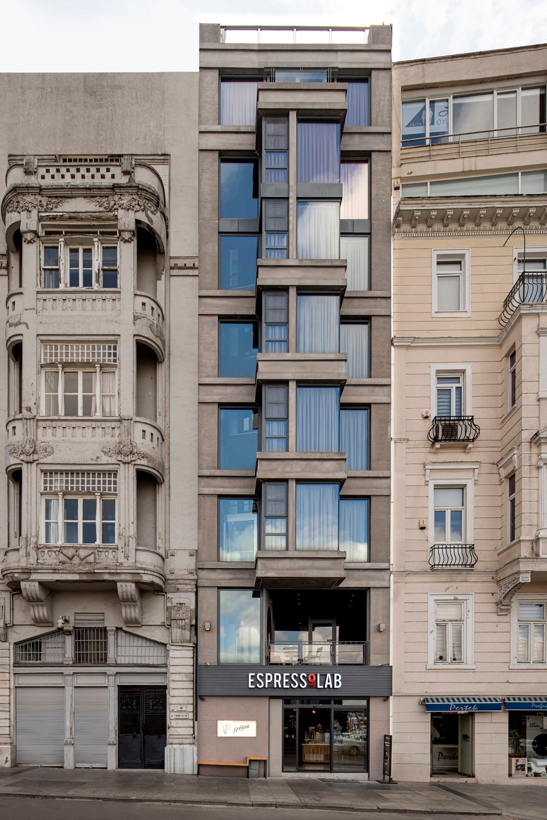 The exterior of the building features a modern facade with large glass windows and a minimalist design. The ground level showcases the entrance to a coffee shop, while the surrounding architecture reflects a blend of contemporary and classic styles.