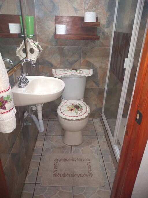 Baño principal con wc , espejo, lavabo con agua caliente y repisa de usos múltiples.
