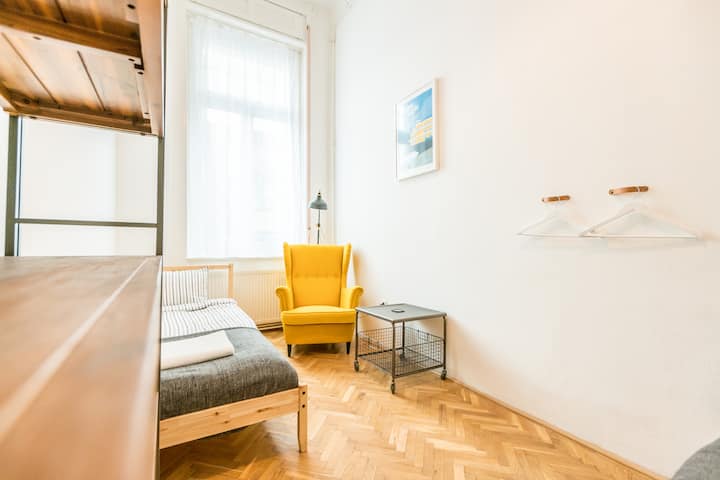 חדר השינה בצד ימין עם שתי מיטות יחיד וכורסה