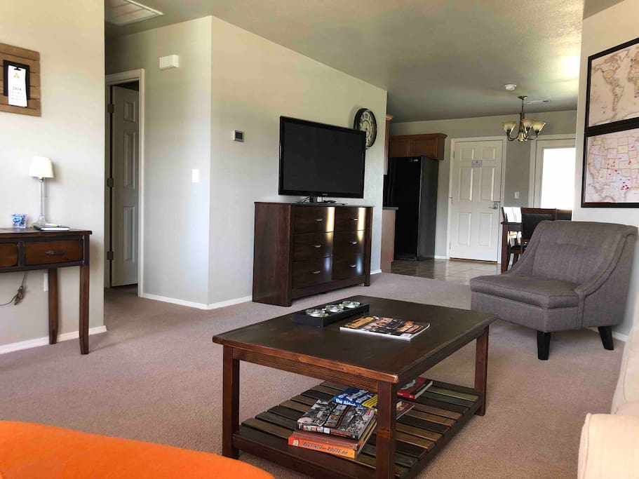 Living Area with couch, tables, two chairs and a 50" TV with premium channels.