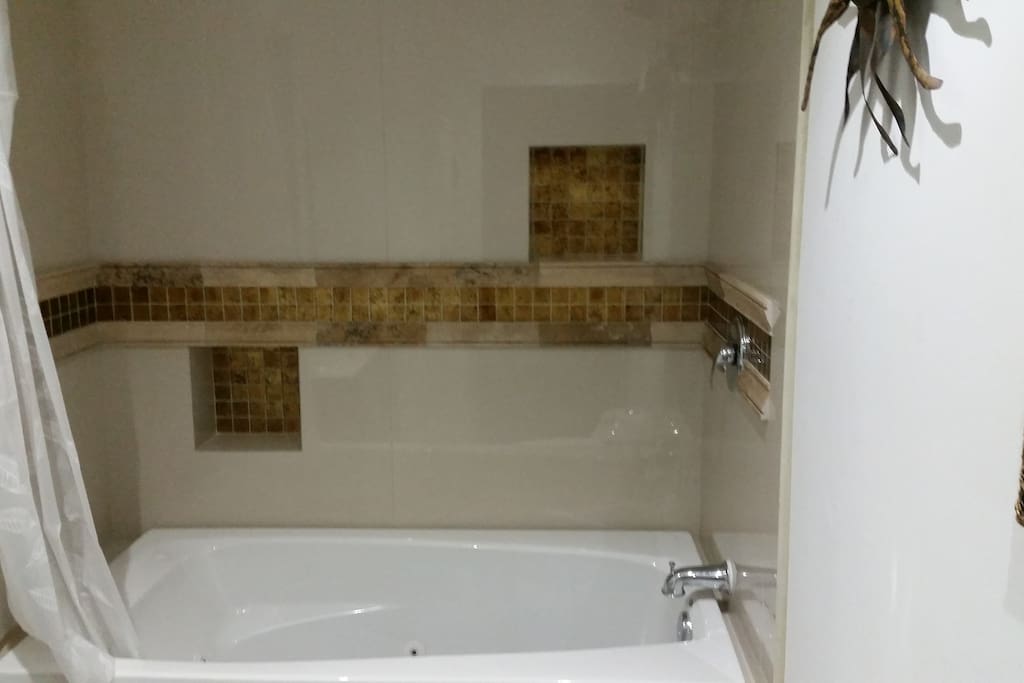 thoughfully decorated bathroom with porceline, travertine, stylistic tiles, lighted sink and jacuzzi tub