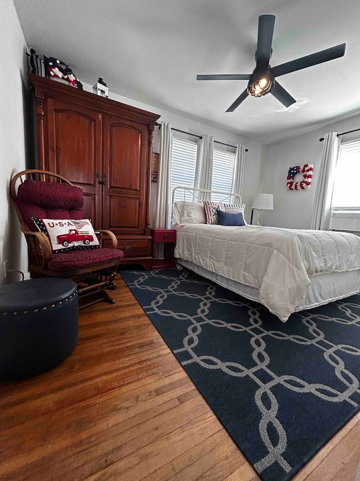 The primary bedroom is outfitted with a queen bed, sound machine(white noise) gliding rocker, ottoman full closet and wardrobe drawers, ceiling fan, and A/C.
