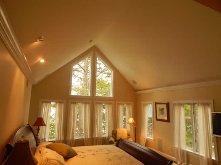 Основна спалня на 1 - ви етаж с изглед към водата, вижте камината и телевизор с плосък екран, баня с мивки, джакузи и голям душ с джетове. 