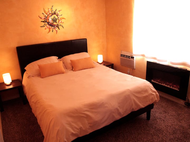 #2 Dormitorio de invitados con cama tamaño queen con colchón de espuma viscoelástica, una cómoda, ventana con vista al acantilado bermellón al este. Aire acondicionado de pared, chimenea eléctrica con calefacción estilo ambiente y luz natural maravillosa. Dormitorio este.