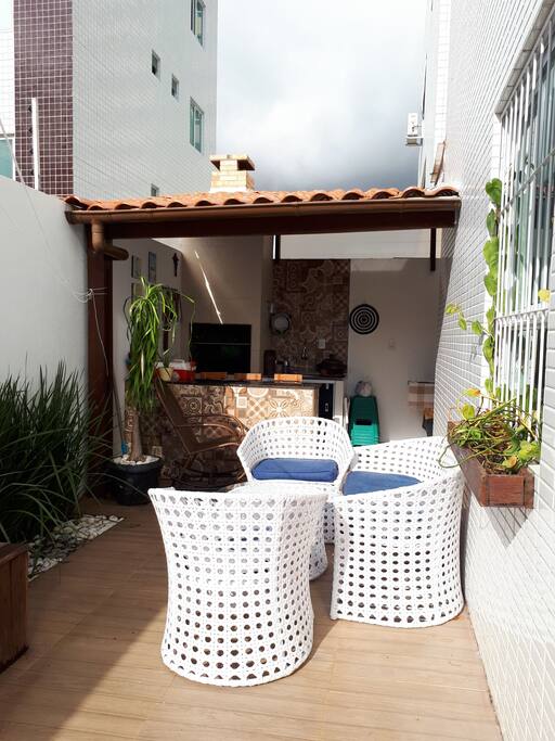 área gourmet, com churrasqueira, bancada e 4 bancos, pia, jogo de mesa e cadeiras para descanso