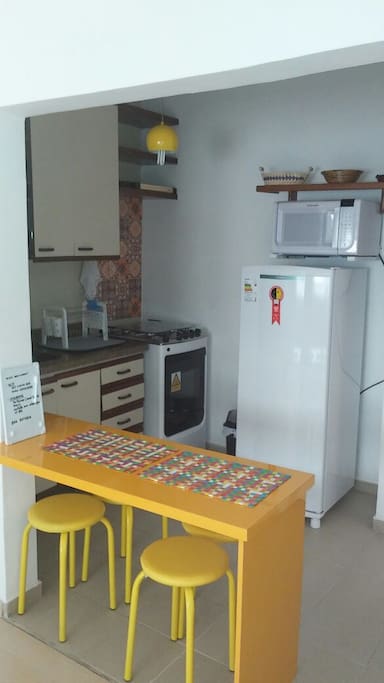 Cozinha americana com fogão, geladeira, micro ondas, cafeteira elétrica e utensílios