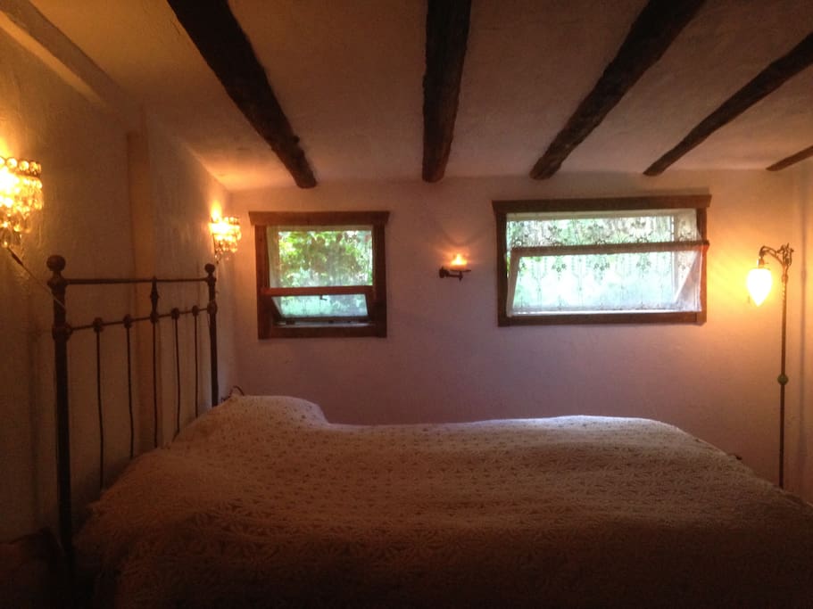 An antique iron, queen bed looks out onto the back garden. The beams in the ceiling date back from pioneer days.