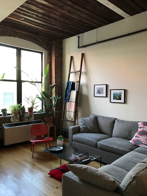Living Room with 14' timber ceilings, exposed brick at windows.