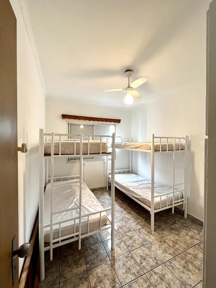 Chumba cha kati kilicho na vitanda 2 vya ghorofa ambavyo vinashikilia watu 4 walio na feni kwenye dari. Dirisha lenye chandarua cha usalama. 