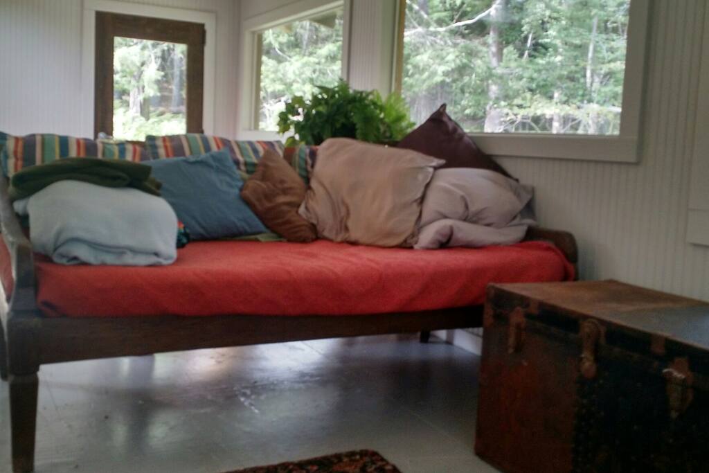 the "third bedroom" listed is a converted porch that wraps around two sides of the house downstairs. It's a spacious area with lots of windows out into the woods and includes this custom daybed and, if desired, a variety of temporary beds can be set up here for more friends to pile in. The "porch" can serve as additional space for lounging, playing and crafting if you wish.