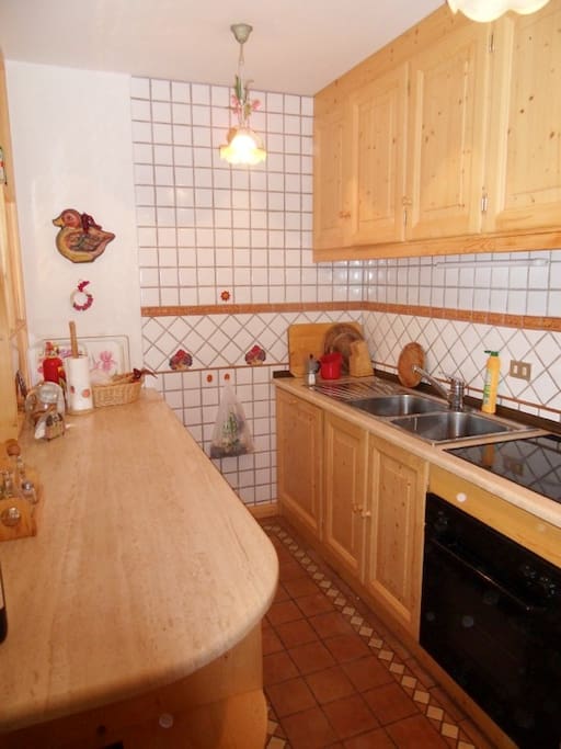 Cucina attigua alla zona pranzo con piano cottura in vetroresina, lavastoviglie e forno elettrico, comodo piano di lavoro in travertino. Dotata di fornita attrezzatura per cucinare.