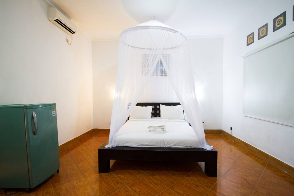 Bedroom with mosquito net and fridge