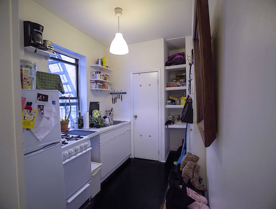 view from outside of the room, hallway, kitchen and sneak peak of bathroom door.