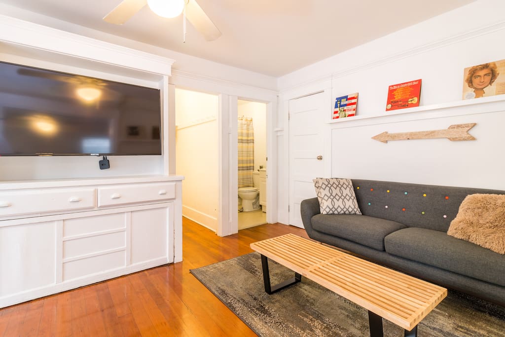 The living area is highlighted by gorgeous wood floors, lots of light, a cozy sofa and large flat screen TV with Apple TV