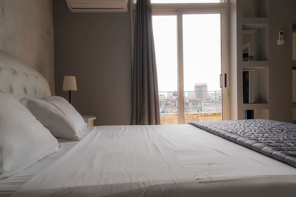 room with queen bed and balcony with beautiful views of the sea and the city