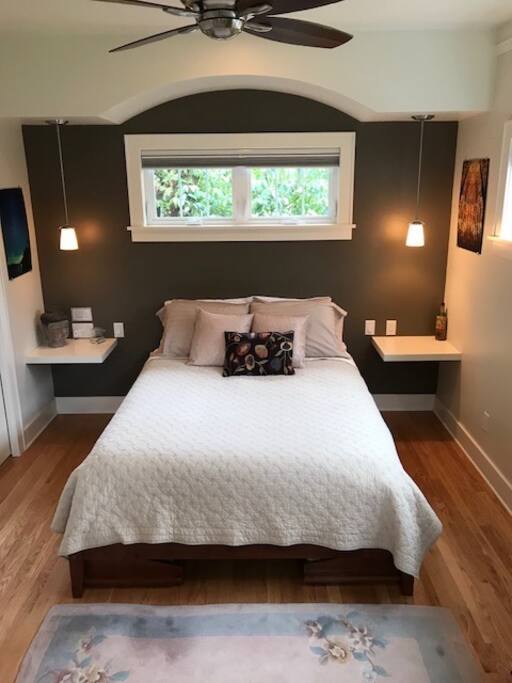 Comfy bed under an arch, a great overhead fan, blackout shades, and easy-to-reach plugs.
