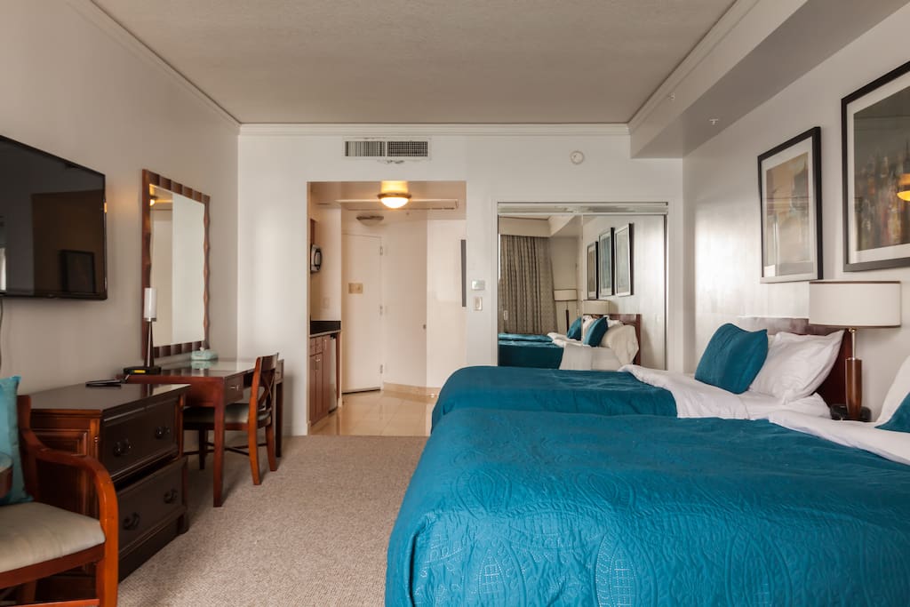 The room is furnished with 2 queen beds, a HD cable TV, a coffee table and 2 single chairs.