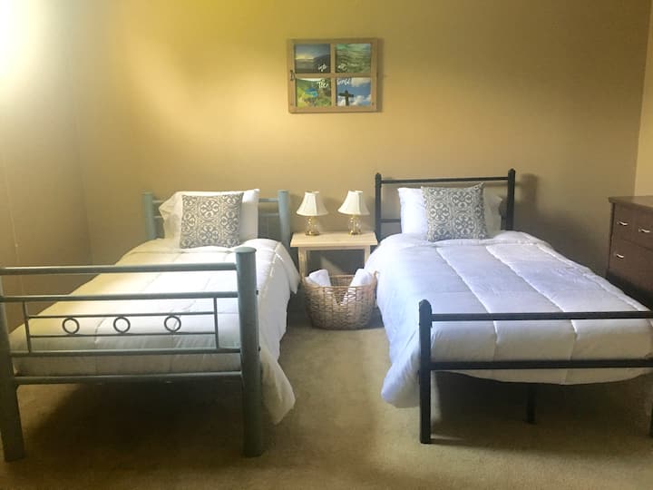 Una cama tamaño queen y dos camas individuales en el dormitorio del sótano.