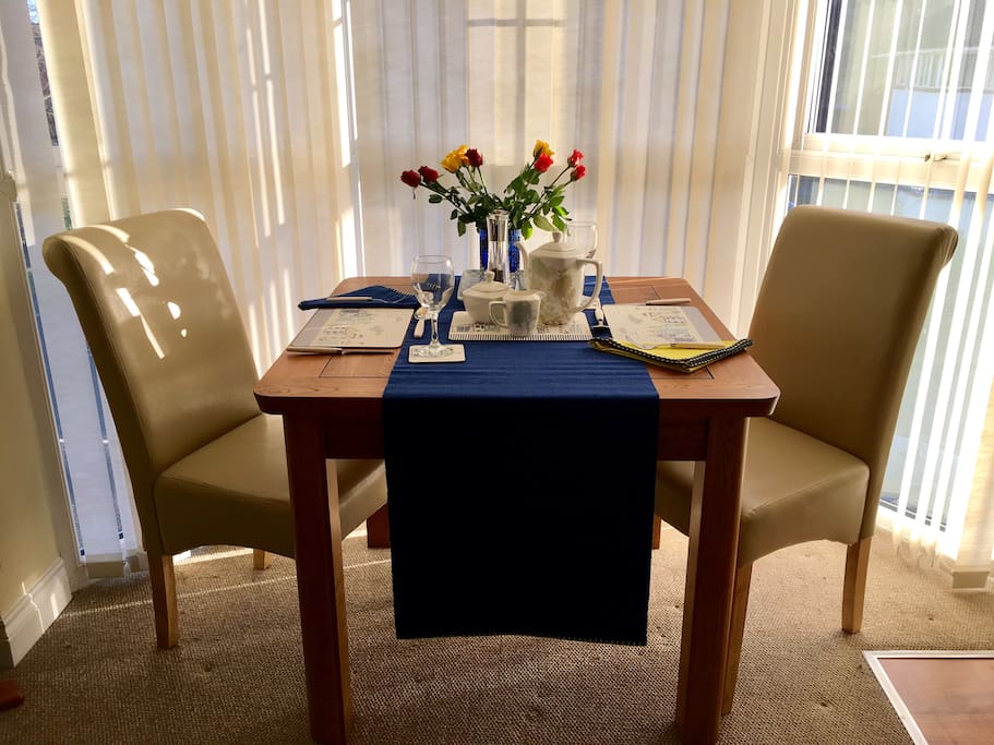 Dining area in bay window with oak table & cream leather chairs