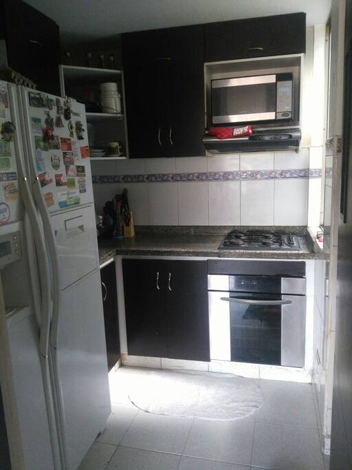 cocina con lavadora, nevera, horno y lo indispensable para cocinar.