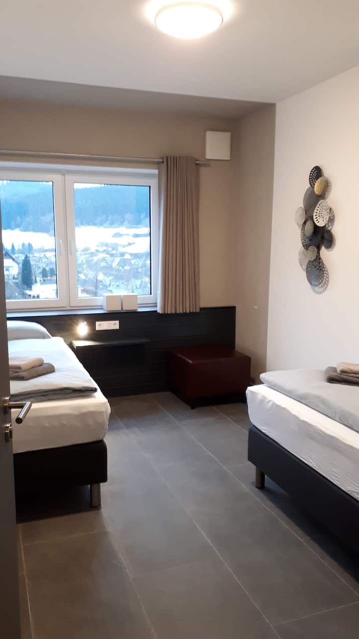 غرفة نوم في الطابق السفلي بسريرين مرتبين بقاعدة زنبركية