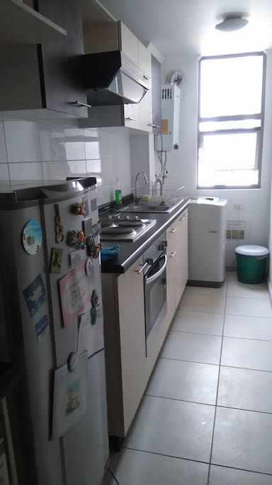 Cocina cuenta con refrigerador, microondas, horno, cocina encimera y campana.