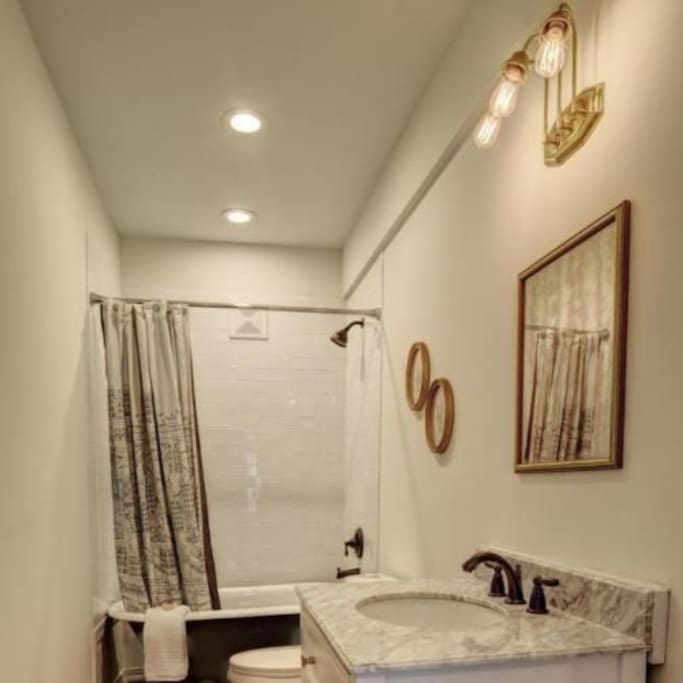 Upon entering at the back entrance, you will immediately see a gorgeous bathroom with subway tile & marble countertops to your right..