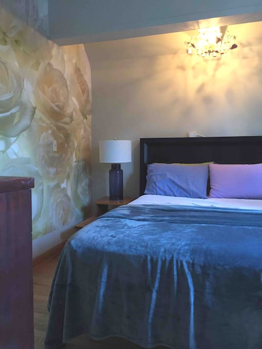 The master bedroom has a mural on the wall and over the headboard is a chandelier with pink crystals.