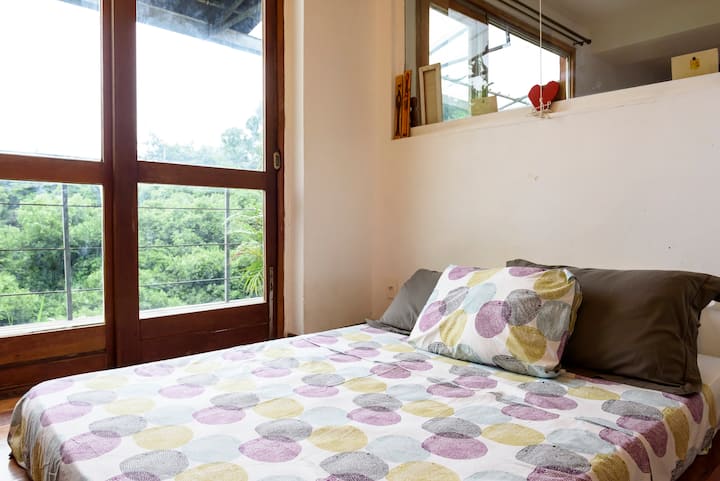 Spálňa s veľkým výhľadom na zeleň a oblohu.
