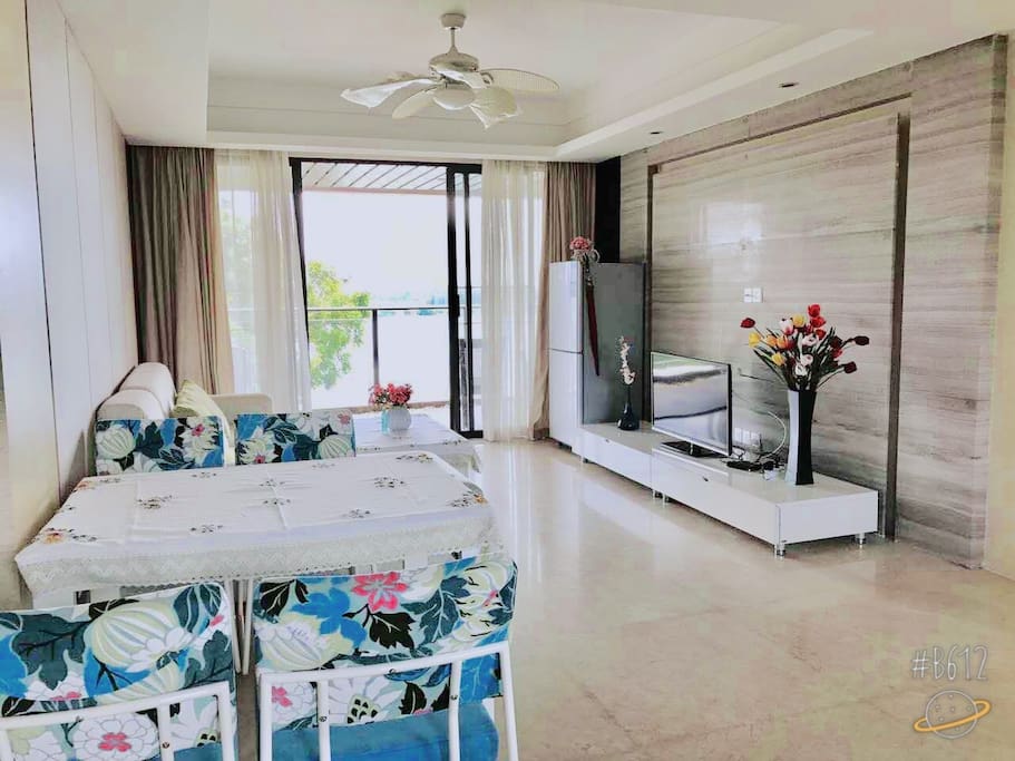 Huge Living room with TV, refrigerator, comfortable sofa, dining table, and chairs.