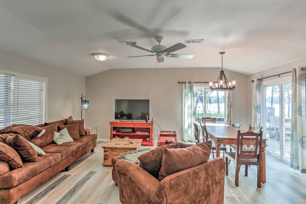 The open living space offers plush furnishings, beautiful wood floors, and views of the water.