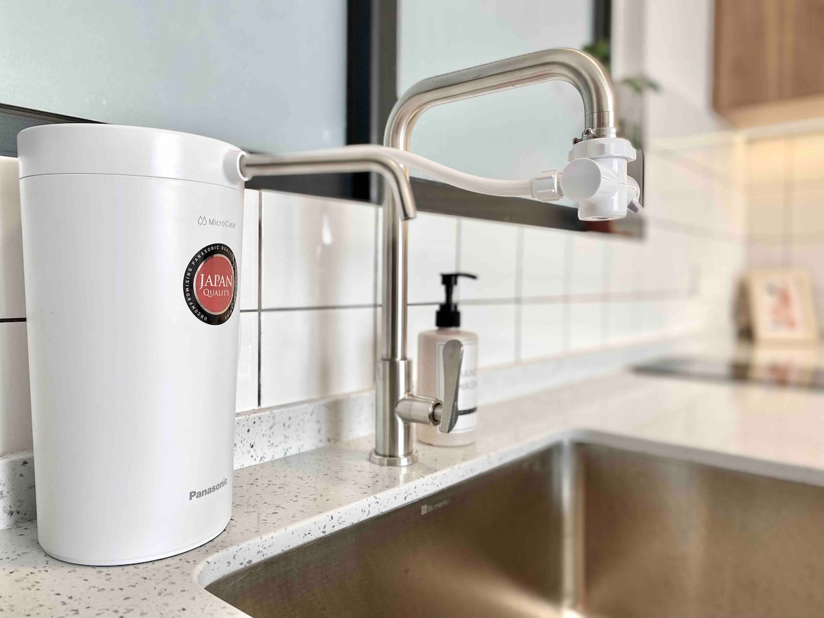A sleek kitchen sink area features a modern water filtration system, illustrating a commitment to quality. Stainless steel faucets complement the clean, minimalistic design, while the gleaming surface of the countertop enhances the practicality of the space.