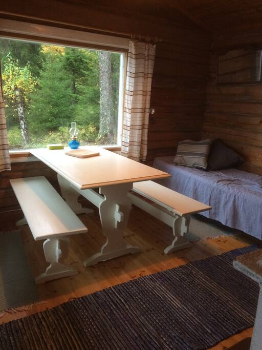 The main room features a traditional table and benches, 2 beds, 2 chairs and a fireplace. Windows to two directions.