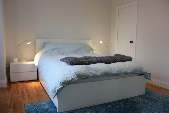 El dormitorio principal tiene una lujosa cama queen y lámparas de lectura junto a la cama. 